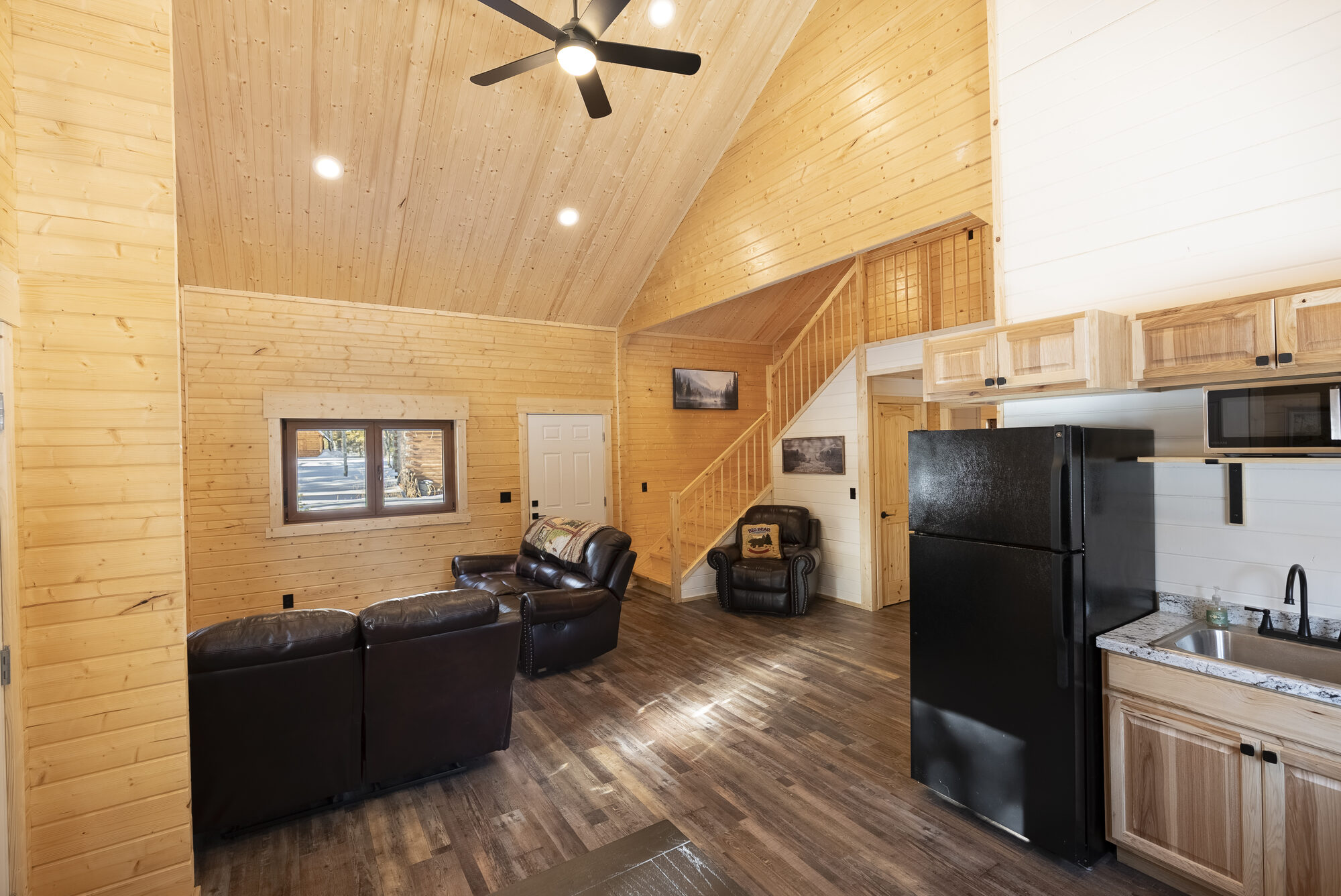 Log cabin living room with loft stairs and kitchen