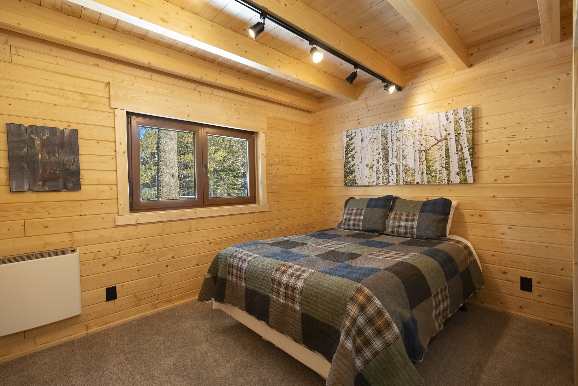 Log cabin bedroom with wildlife art and plaid bedding
